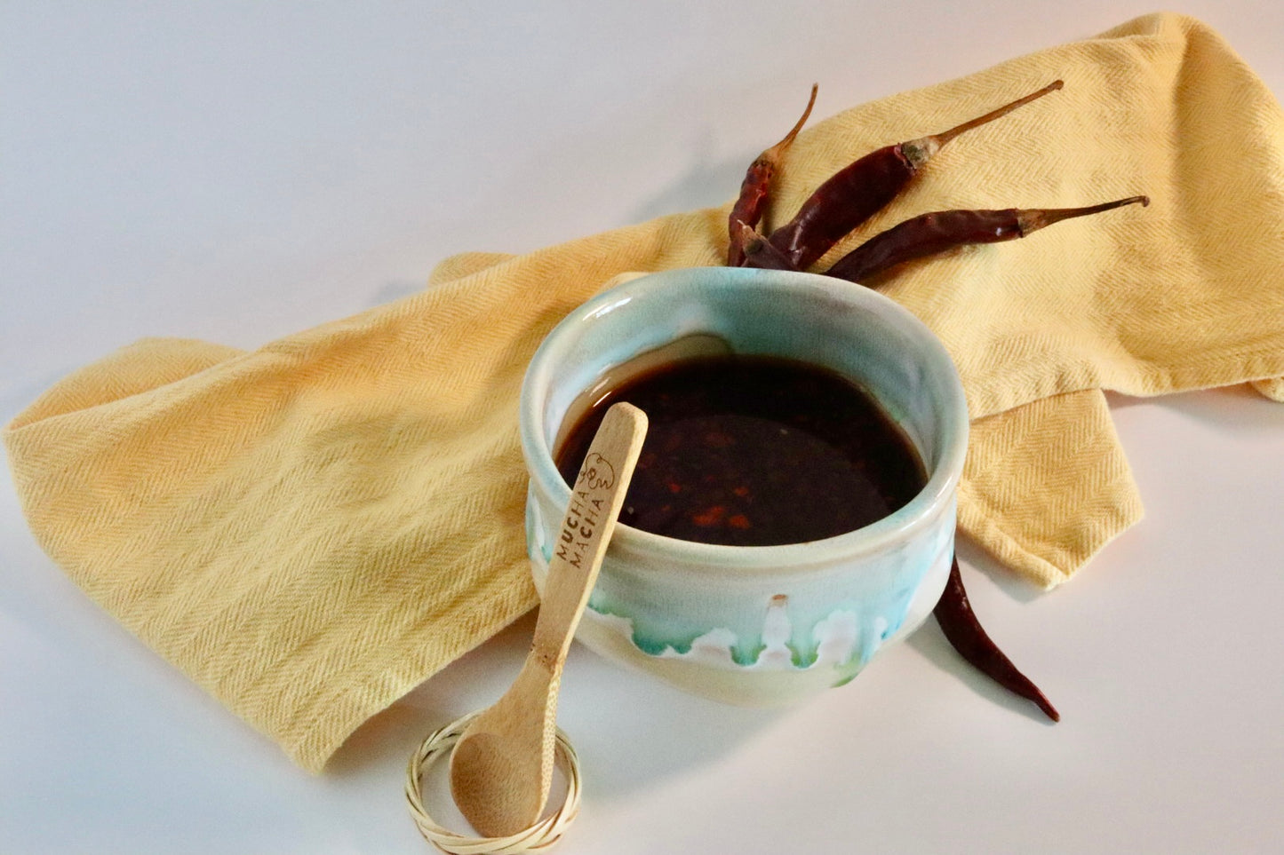 Small bowl of dark liquid with a wooden spoon on a yellow cloth